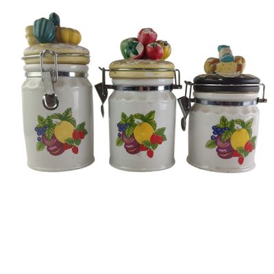 three white ceramic canisters with fruit designs on them