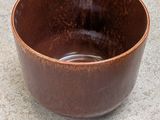 a brown bowl that is sitting on the ground