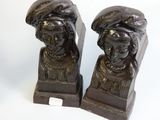 pair of cast iron busts of women with hats on their heads