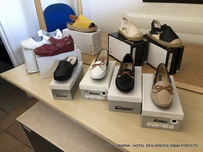 Plusieurs paires de chaussures pour femmes sont posées sur des cartons, sur une table.