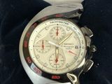 silver watch with red hands on a black cloth with a tag on it