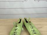 pair of green leather shoes with laces on a wooden table