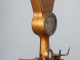 a gold clock on a stand on a wooden table