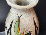 a white vase with a design on it sitting on a stand