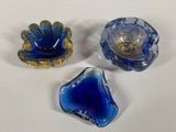 three blue glass bowls sitting on top of a white table