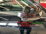 reflection of a man in a car ' s rear view mirror in a shop