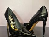 black high heeled shoes on a black table with a white wall in the background
