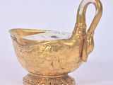 a gold vase with a swan handle on a white background