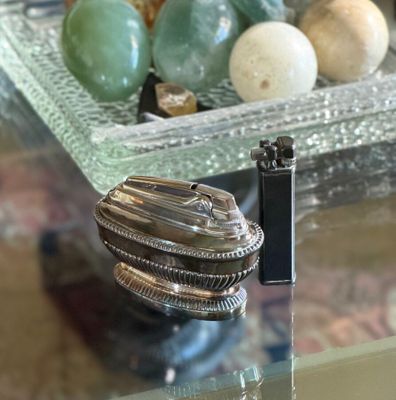 a silver object on a glass table next to a camera