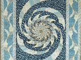 a blue and white quilt with a spiral design on it