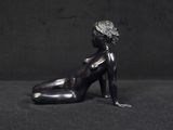 statue of a woman sitting on her stomach on a black background