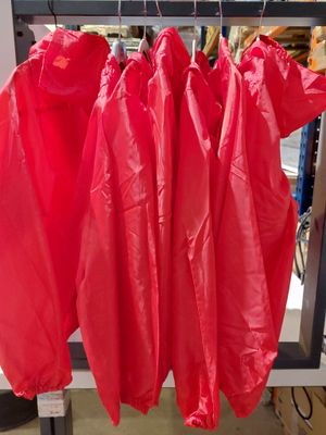 three red raincoats hanging on a rack in a store