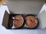 un coffret contenant deux poudres compactes, présenté dans une boîte en carton