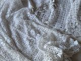 une couverture blanche au crochet posée sur un lit, à côté d'un oreiller