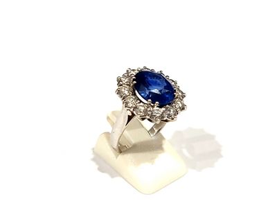 une photo d'une bague sertie d'un saphir bleu et de diamants, posée sur une surface blanche