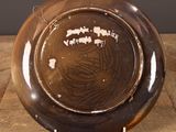 a brown plate on a wooden table with a black background