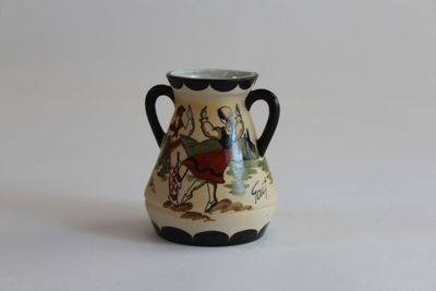 a small vase with a horse on it on a white surface