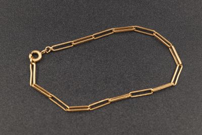 gros plan d'un bracelet en chaîne en or sur une surface noire
