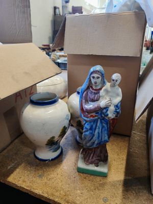une statue représentant une femme tenant un bébé et un vase posés sur une table