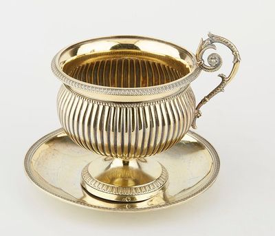 an antique silver cup and saucer with a saucer on a saucer
