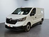La camionnette blanche est garée dans une grande pièce au sol noir.