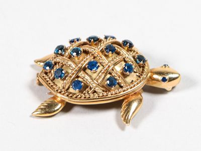 une broche en forme de tortue en or, ornée de pierres bleues