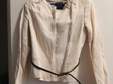 beige jacket with black belt on hanger on wall next to door