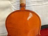 an orange violin sitting on top of a red case next to a white sheet