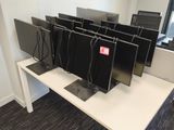 four computer monitors on a white desk in an office
