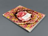 the book is open on a gray surface with a pink flower
