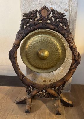 a large metal gong on a stand on a wooden floor