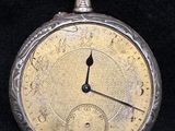 a silver pocket watch on a black background