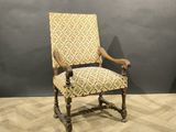 une vieille chaise en bois dont le dossier et les accoudoirs sont recouverts d'un tissu à motifs