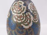 un vase bleu et vert posé sur une surface blanche