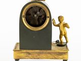 a small statue of a boy standing next to a clock