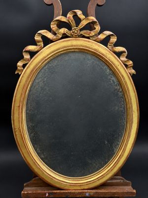 un miroir ancien dans un cadre doré, posé sur un socle en bois, avec un fond noir