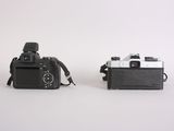 two cameras sitting next to each other on a white surface