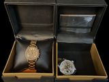 two watches sitting in a box on a black surface