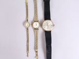 two watches and a bracelet are sitting on a white surface