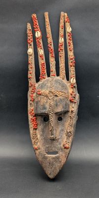 un masque en bois orné de motifs rouges et blancs