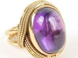 a gold ring with a purple stone surrounded by a rope