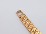 a close up of a gold bracelet on a white surface