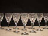 six empty wine glasses lined up on a table in front of a black background