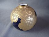 a gold and blue vase on a gray surface