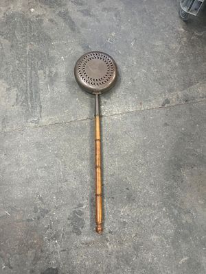 a metal strainer with a wooden handle on the floor