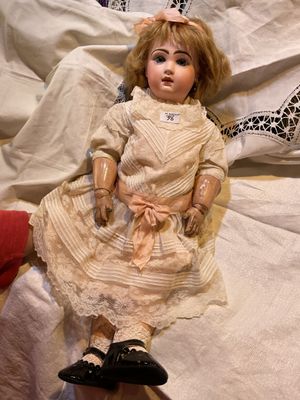 a doll that is sitting on a bed next to a pillow