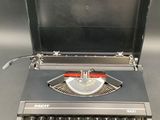 une vieille machine à écrire posée sur une table, son capot ouvert