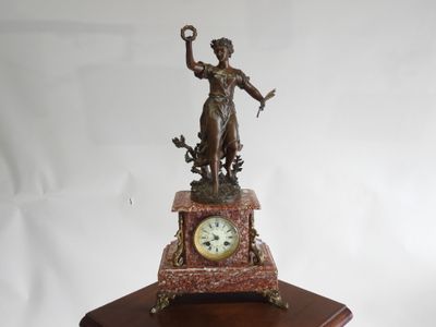 une statue de femme tenant une horloge sur une table