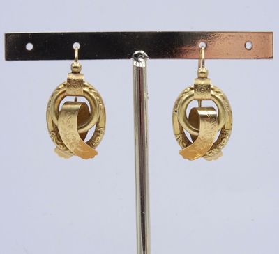 paire de boucles d'oreilles dorées, ornées d'un motif circulaire monté sur une tige métallique