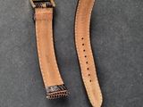 two pieces of brown leather with a gold buckle on a black surface